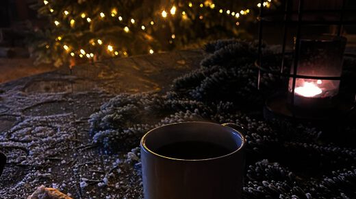 Heißer Glühwein und Laterne vor dem beleuchteten Weihnachtsbaum