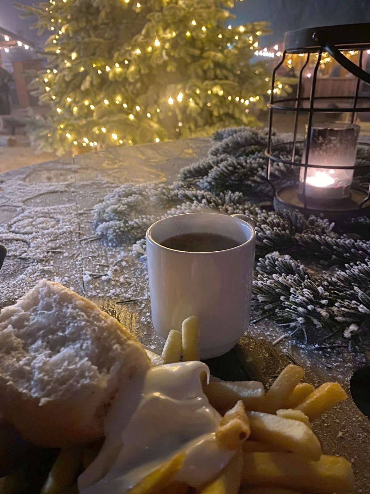 Heißer Glühwein und Laterne vor dem beleuchteten Weihnachtsbaum
